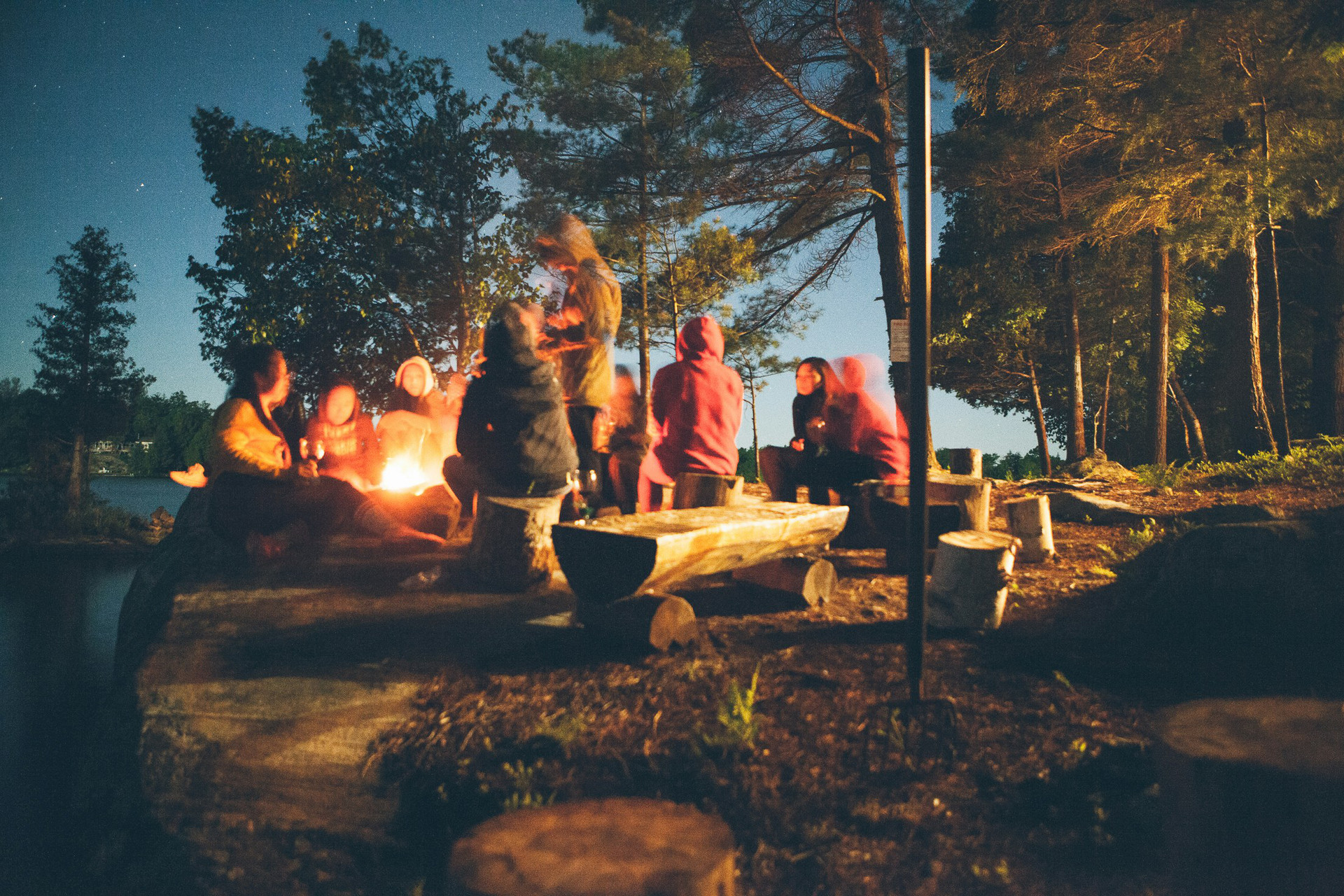 teens at campfire in wooded area under night stars