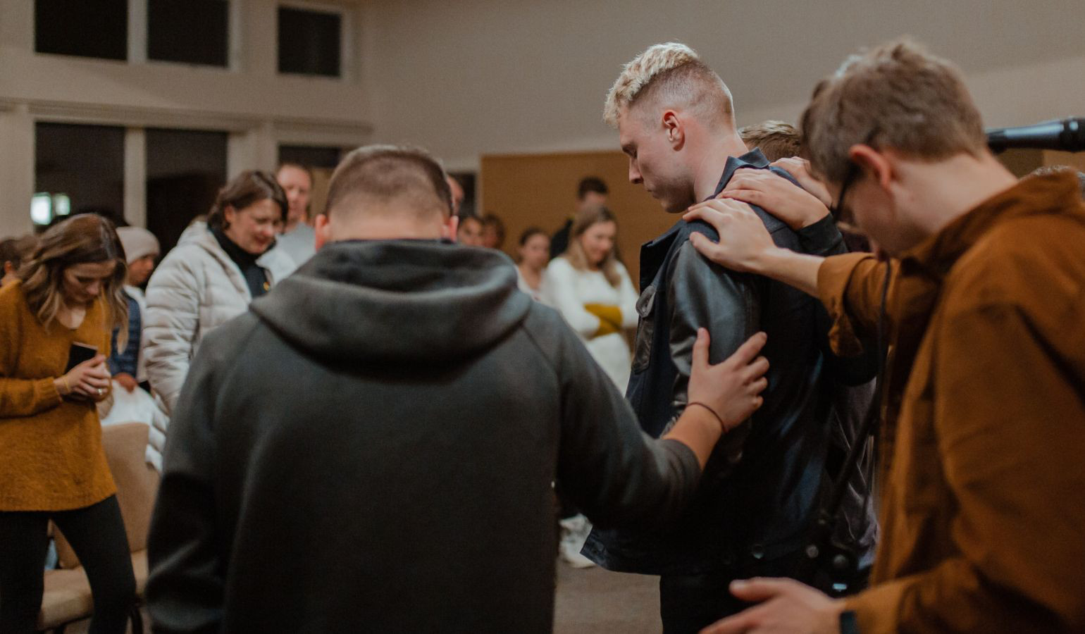 Youth gathering where a few men praying over a young man