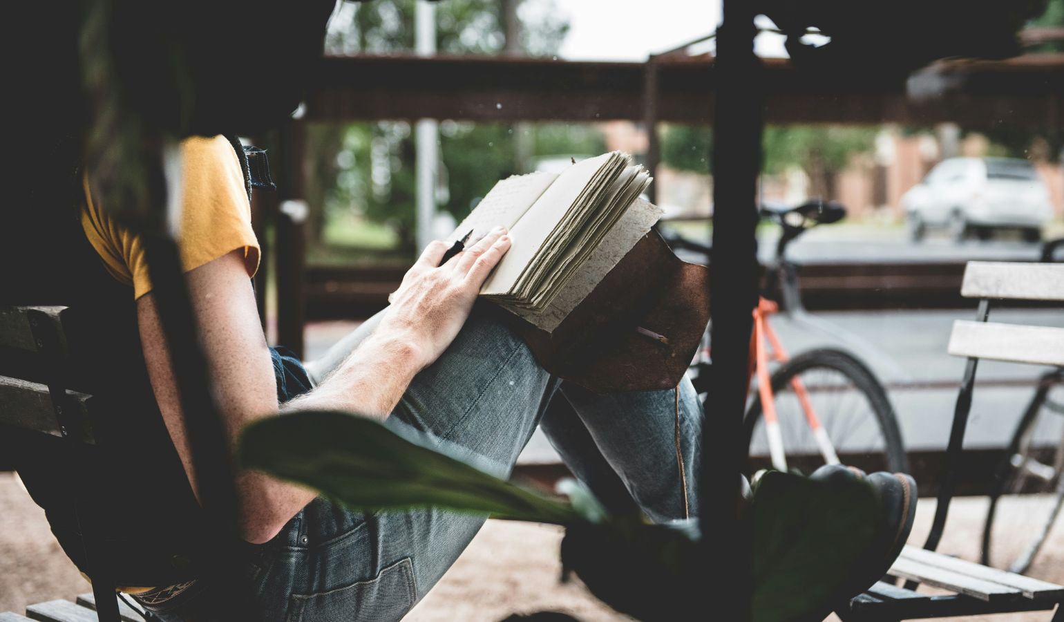 Young woman sitting outside with feet up on a chair journaling.