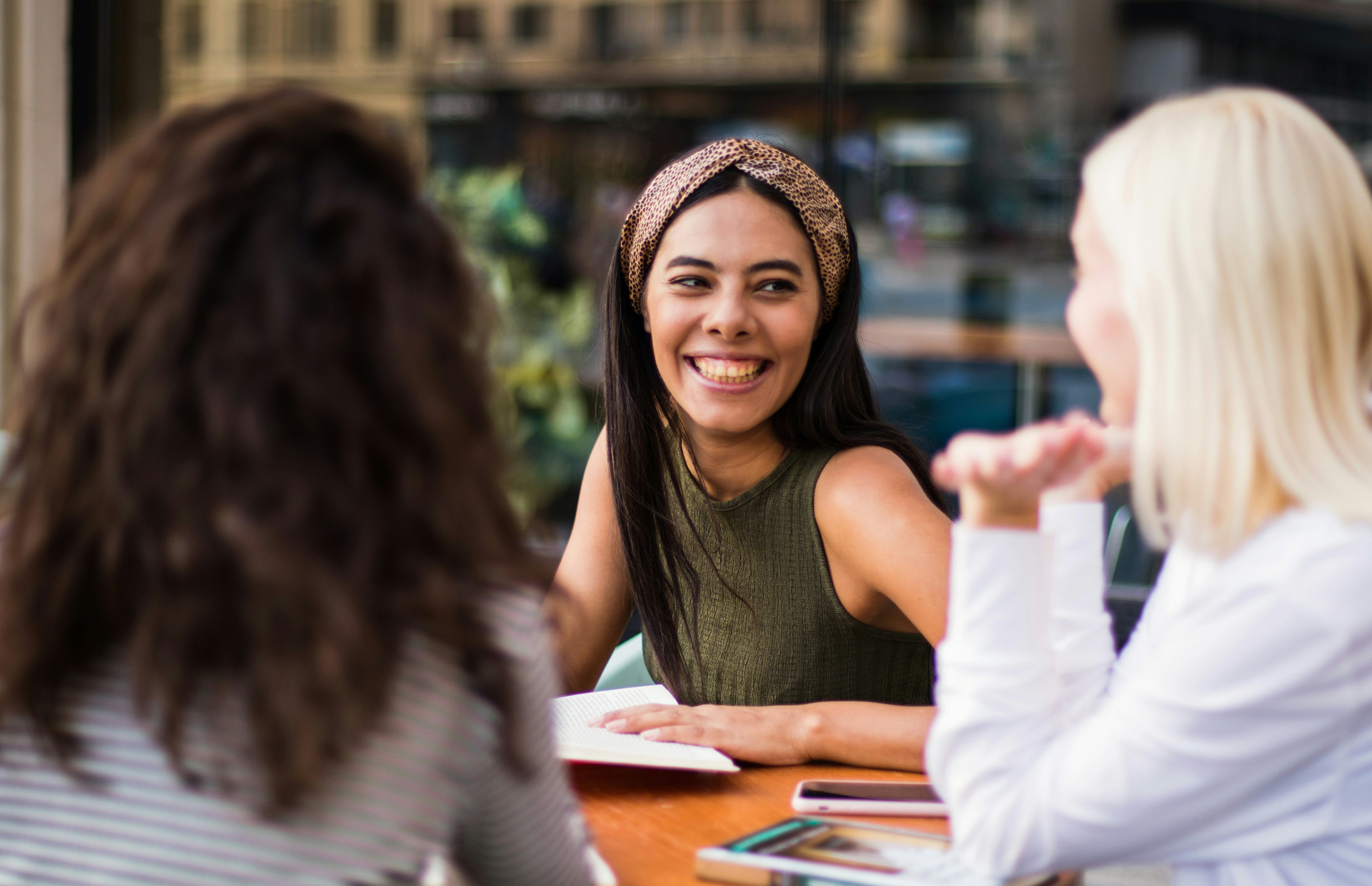 Multicultural young women sitting at a table doing a bible stufy happily.