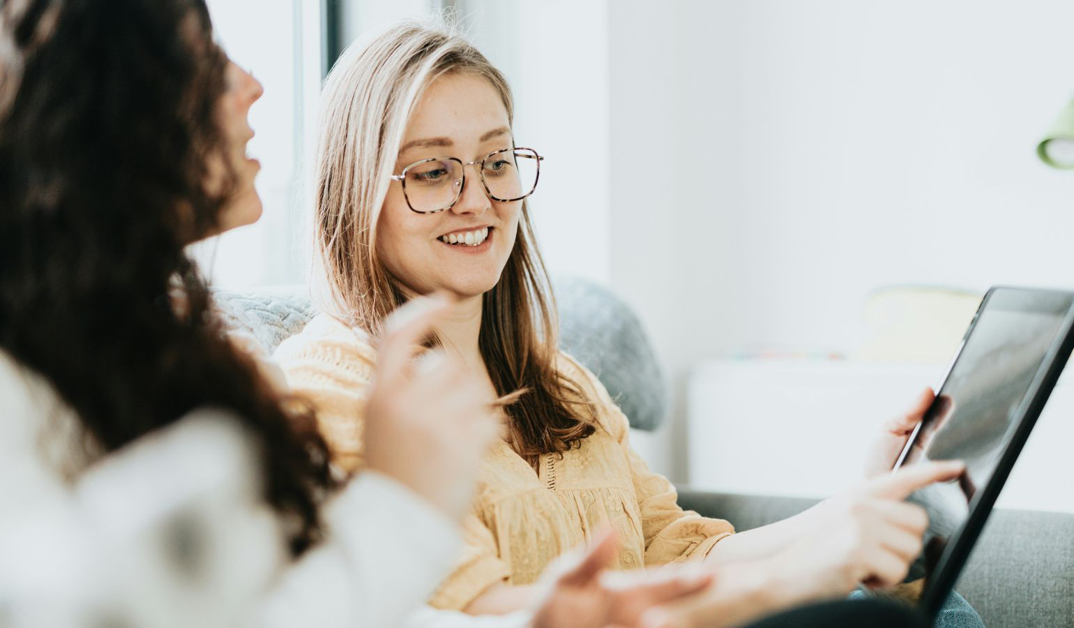 Young women sitting talking and pointing at a computer.