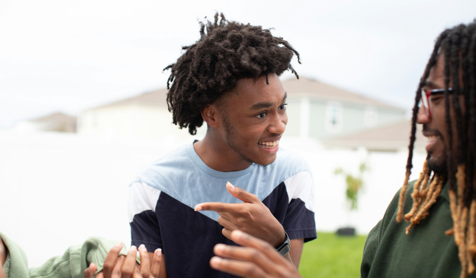 Two african american men, one younger teen and one adult, talking, smiling and looking at eachother