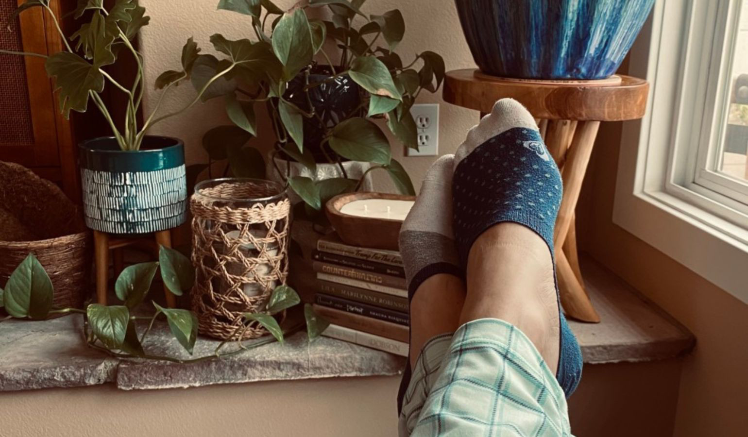Legs crossed, feet propped up onto a bench with potted plants.