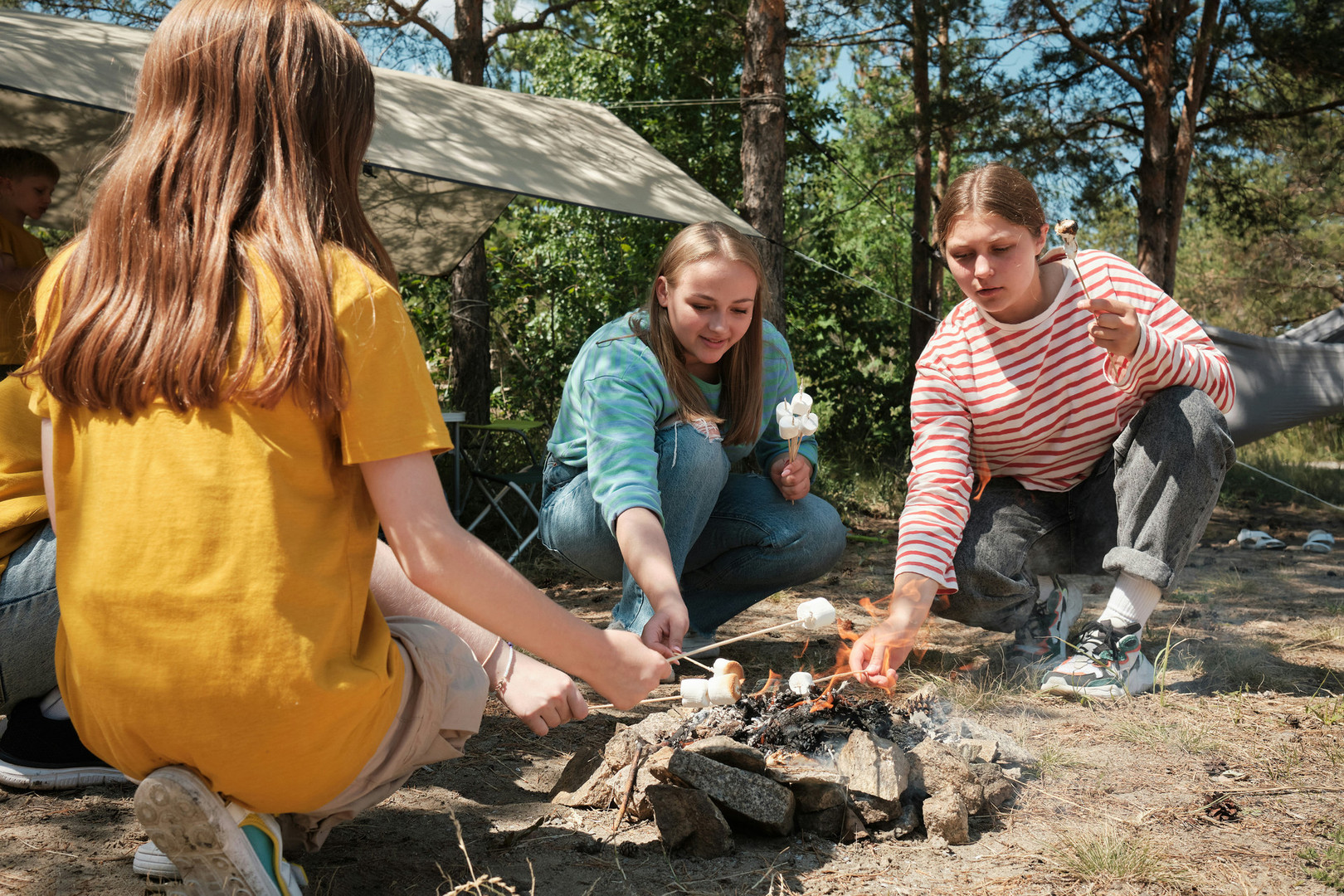 Three female students roasting marshmallows at a campfire