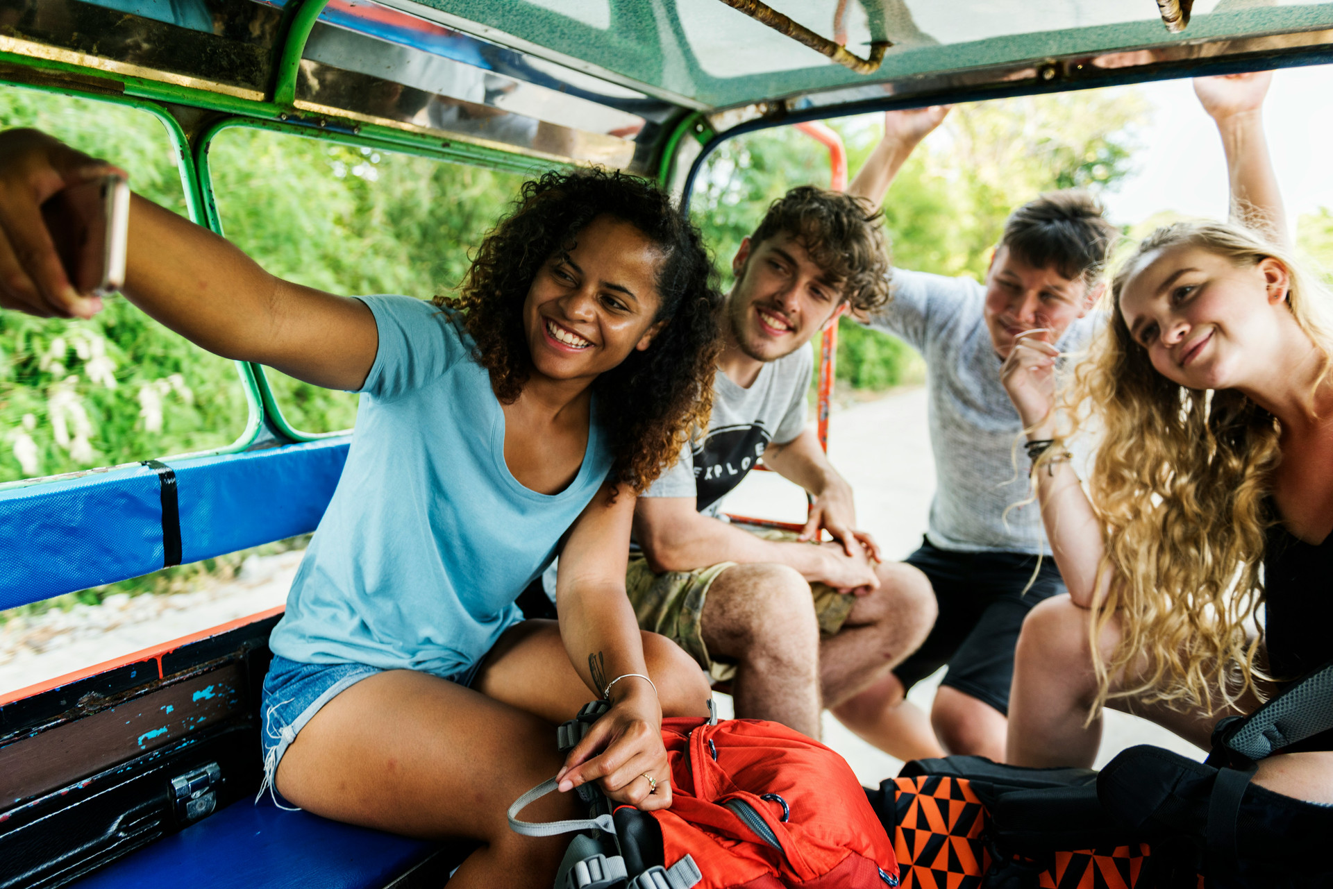Students in the back of a car with traveling gear taking a selfie.