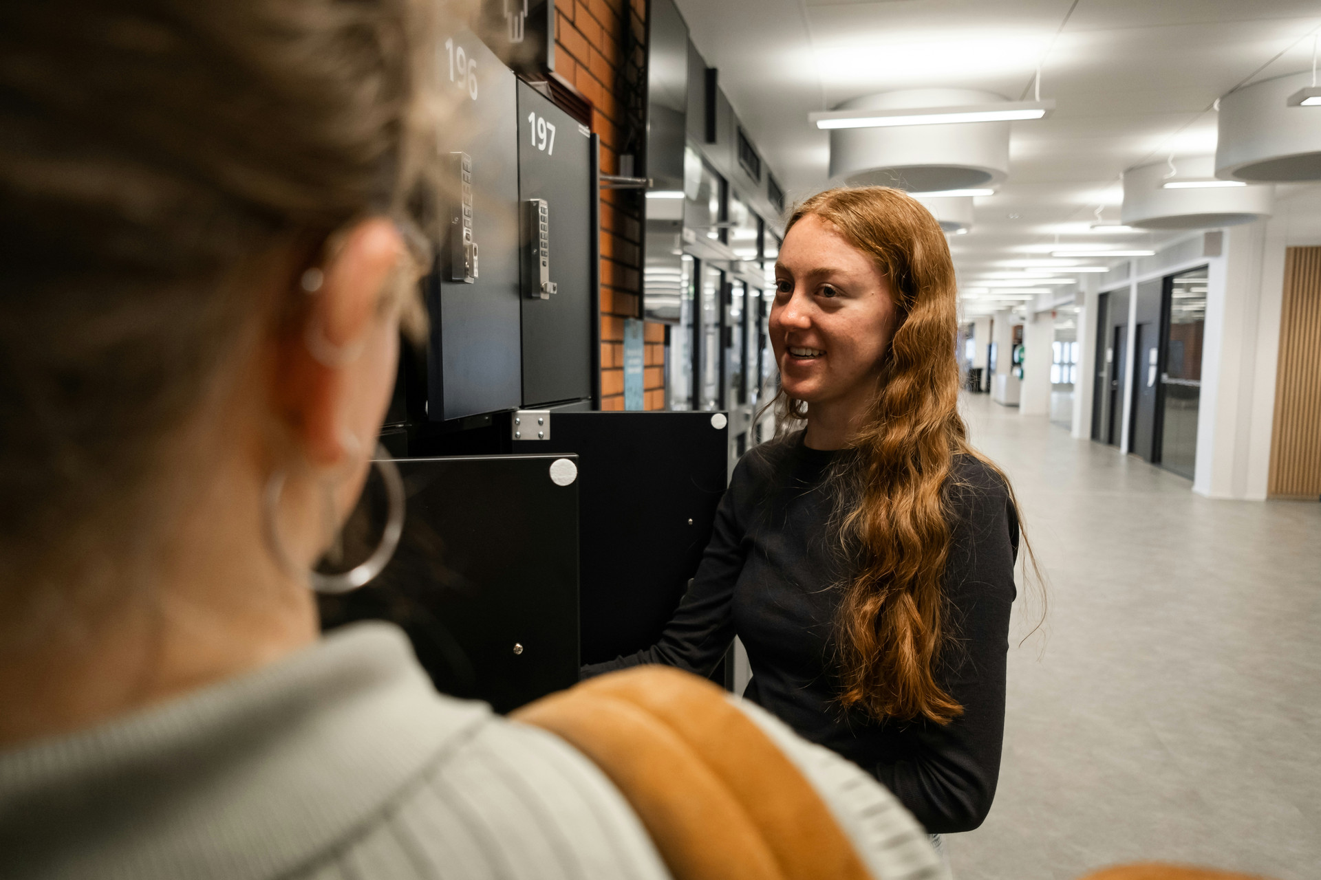 Two young Ladies talking by their lockers in the hallway