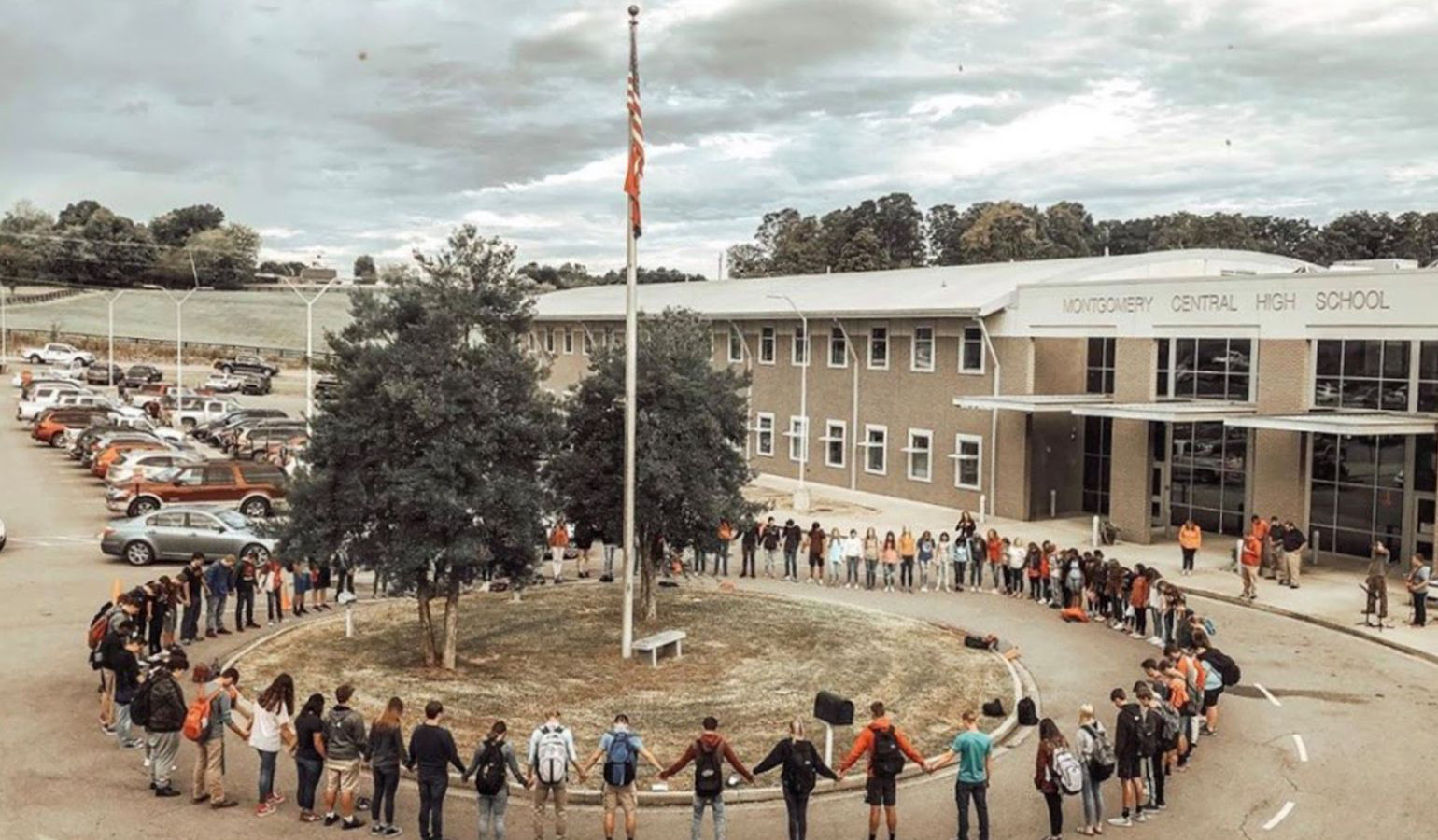 Students gathered in a circle around a flag pole