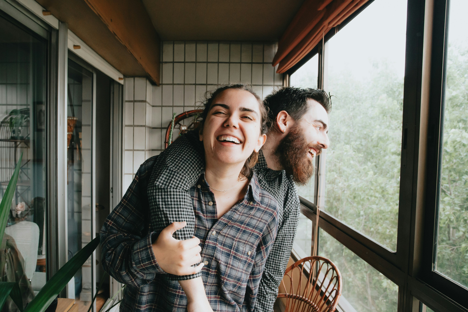 Couple laughing, husband behind with his arm over wife's shoulder