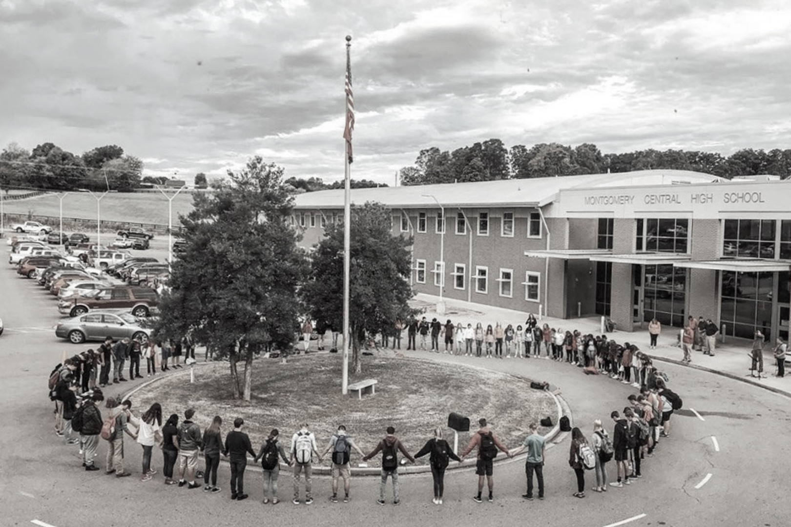 Students praying in a circle around a flag pole at their school