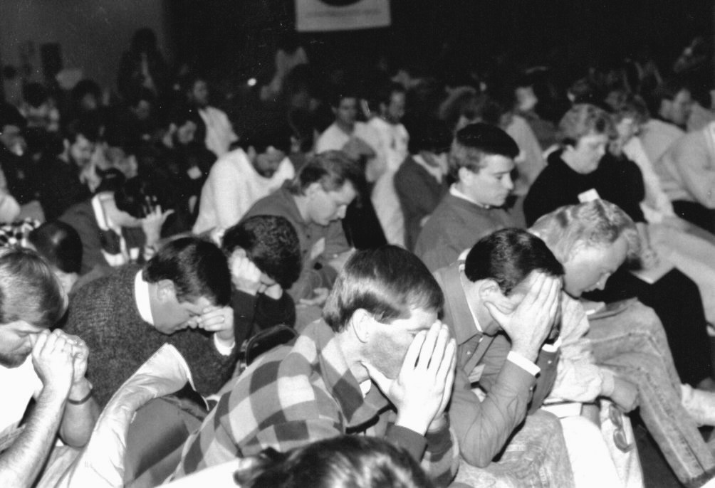 Men at a conference with heads bowed in prayer