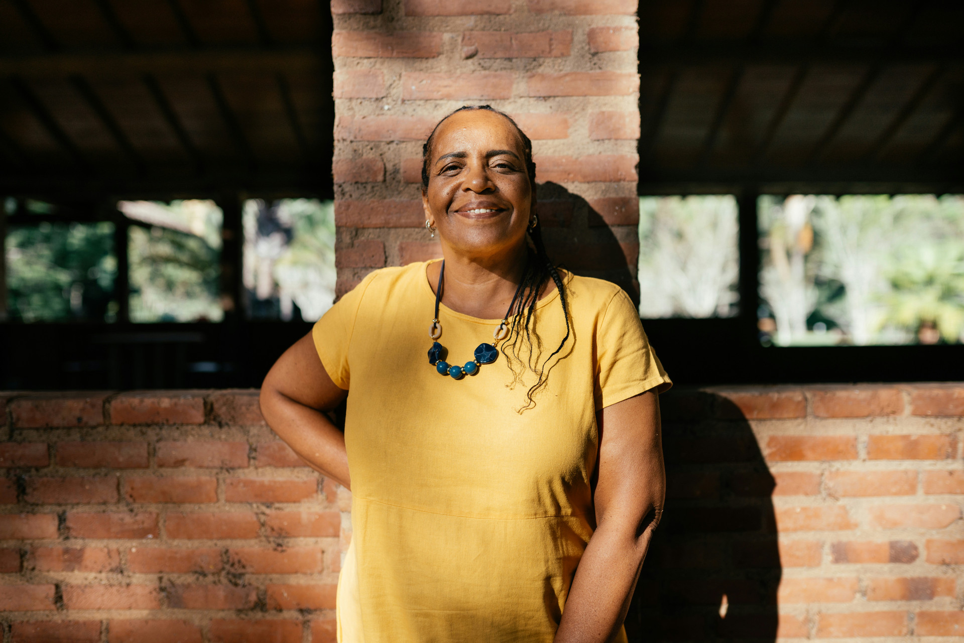 Woman smiling and standing in front of a brick wall.