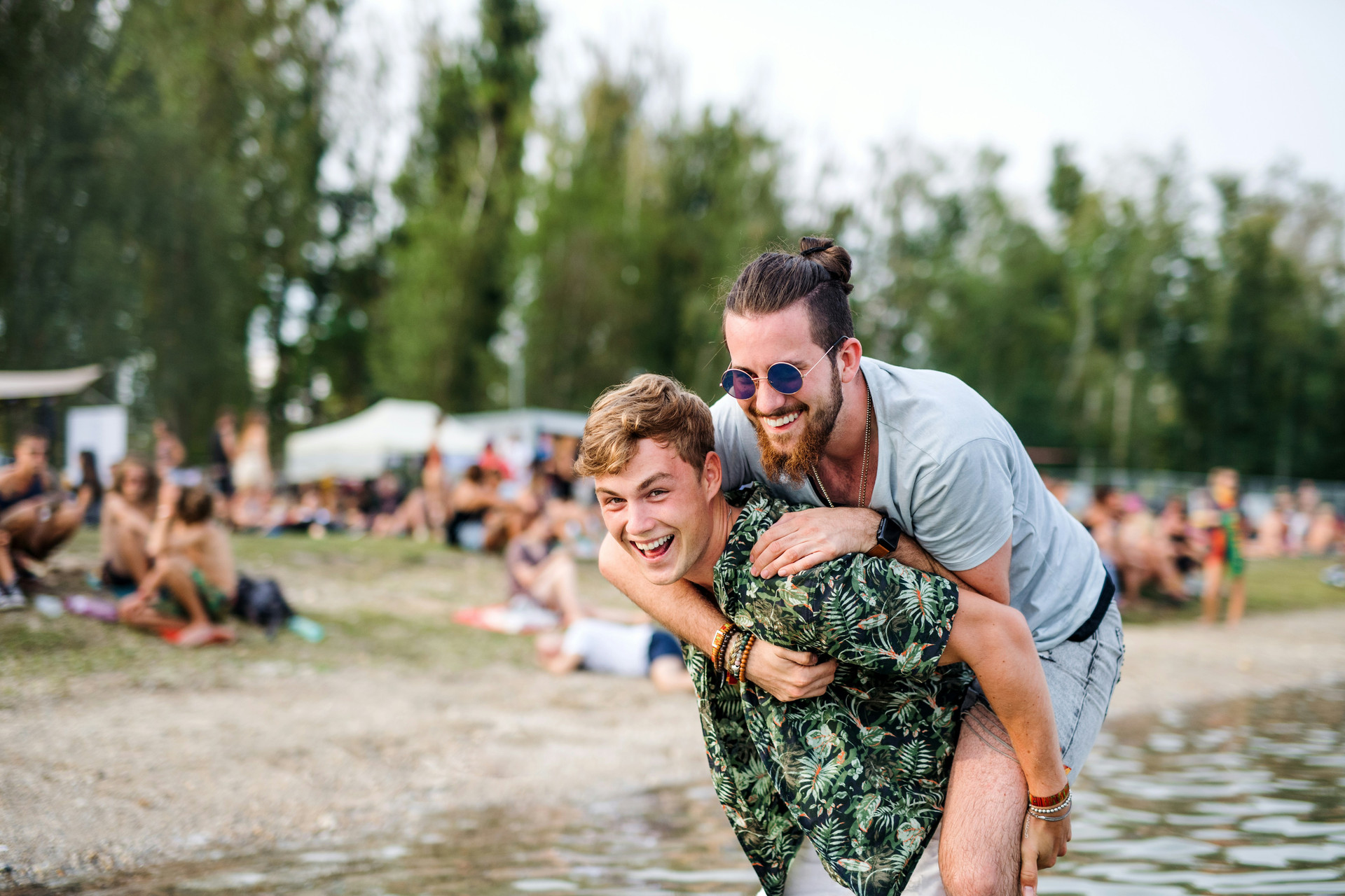 Young man giving another young man a piggy back ride at a lake at camp