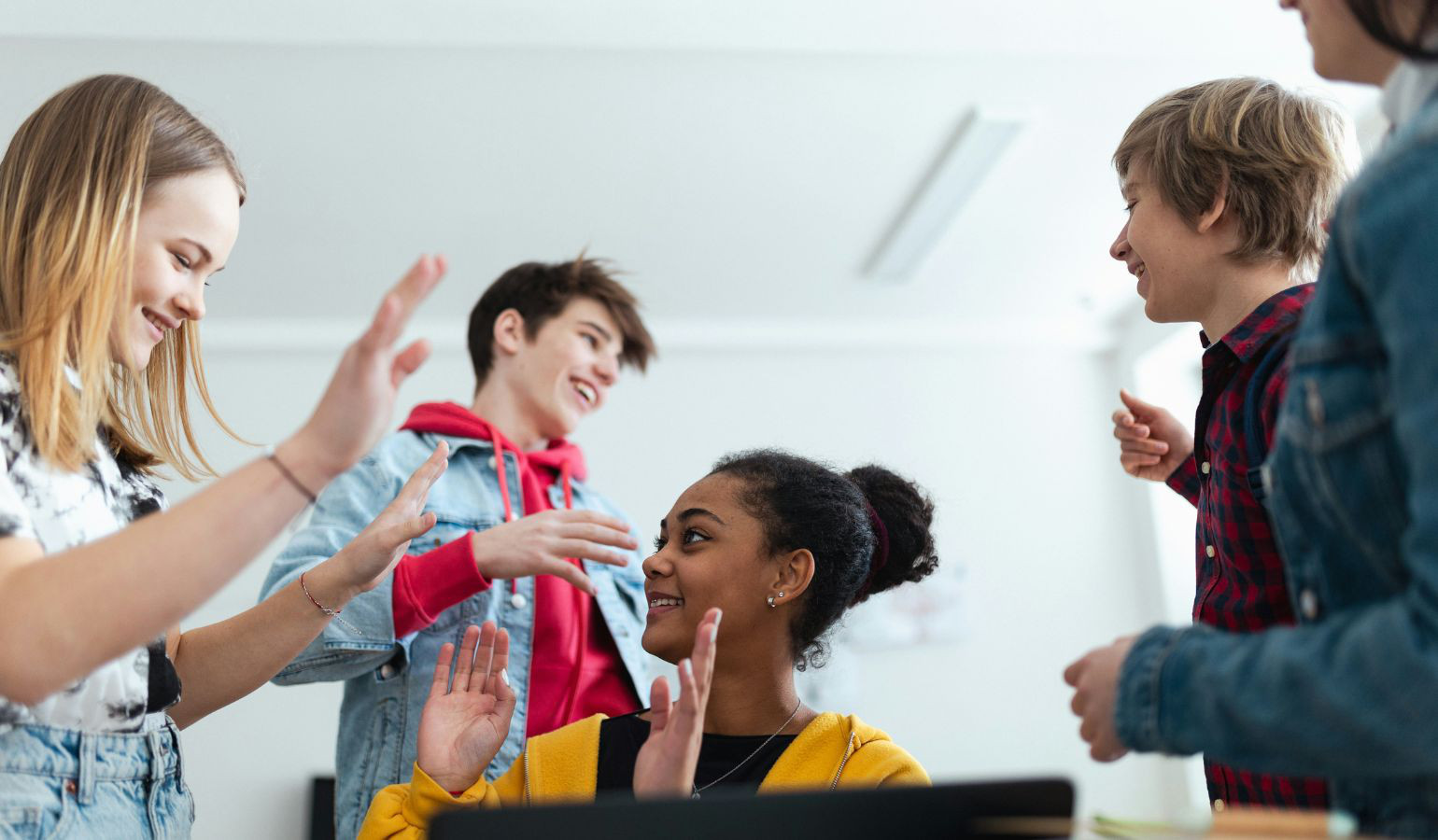 teenagers in a classroom smiling and high fiving