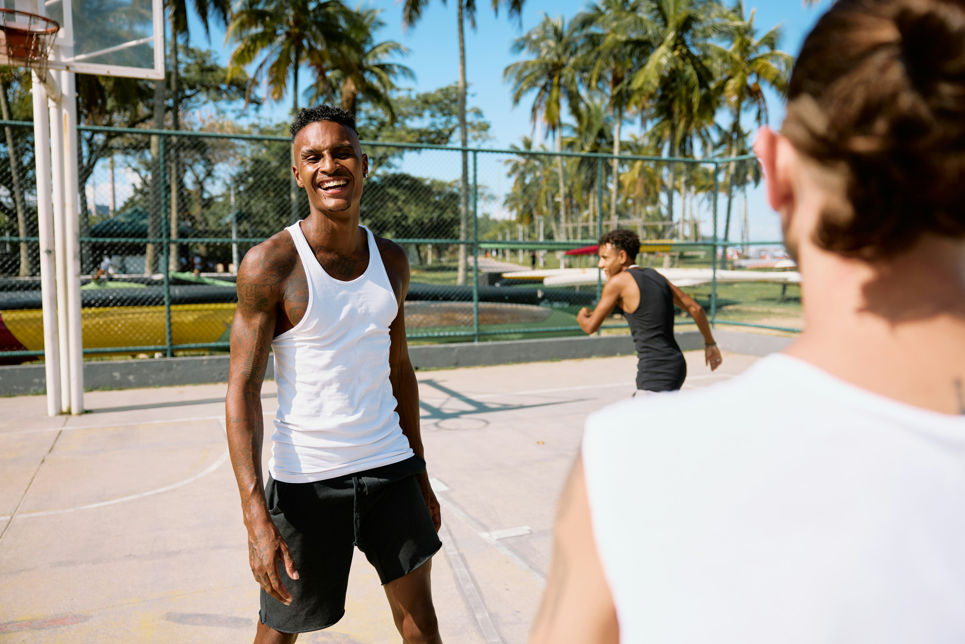 Young men playing basketball on a fenced in court