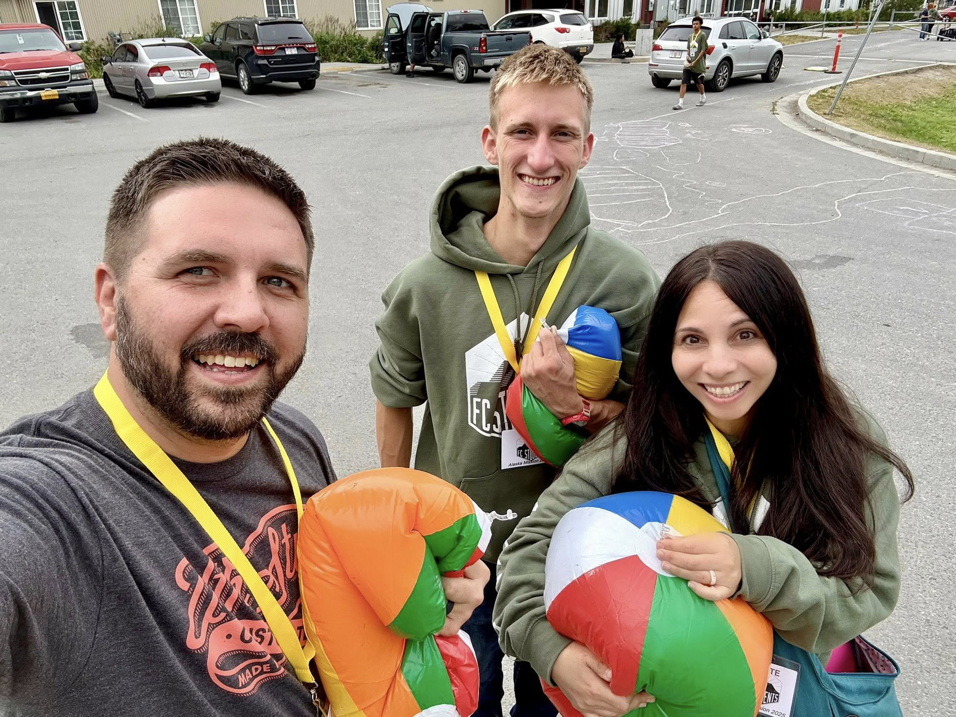 Steve, Yvette and a teen smiling while holding beach balls