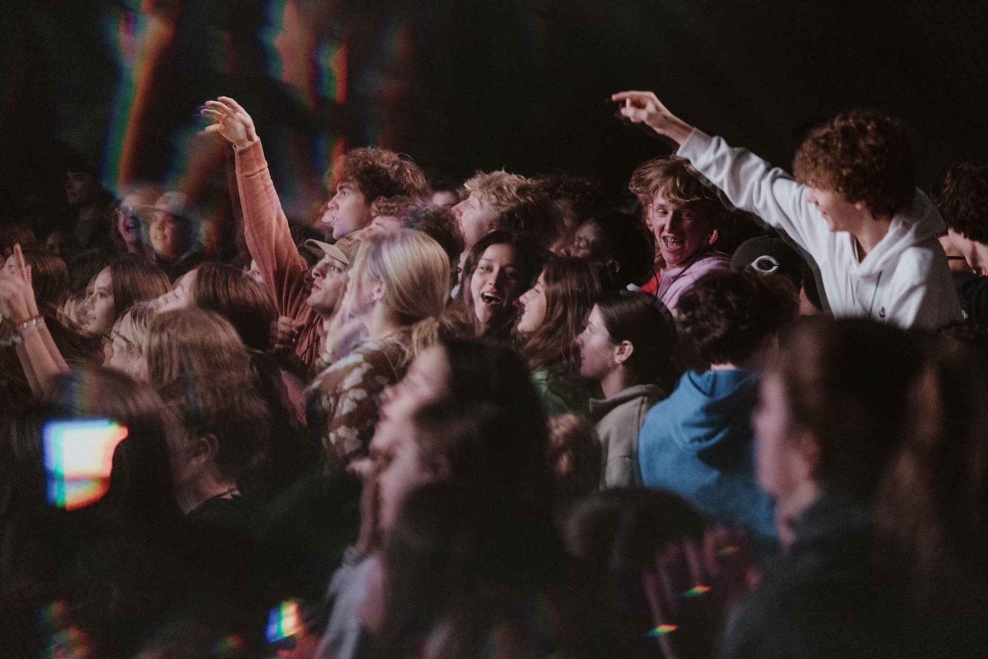 Dark concert hall with teenagers looking and praising.