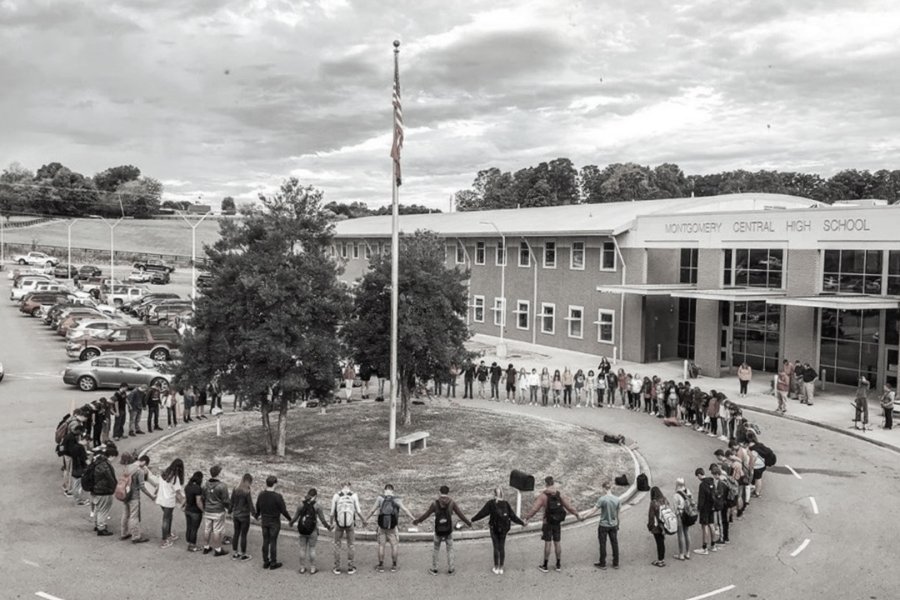 Students praying in a circle around a flag pole at their school