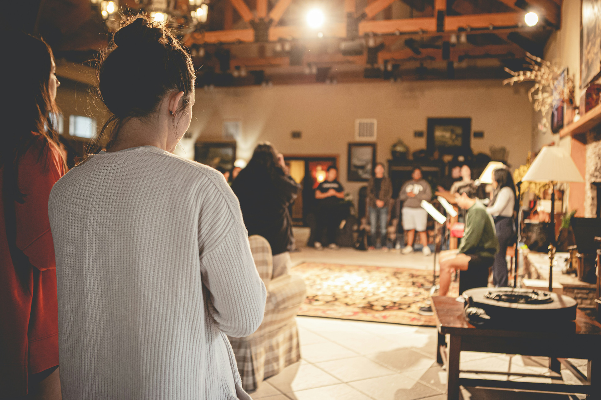 group of young people praying in a circle around a living room